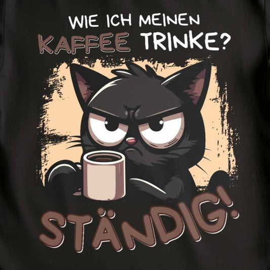 Nahaufnahme eines schwarzen Damen-Shirts mit Design einer Kaffee trinkenden schwarzen Katze und lustigen Spruch: 'Wie ich meinen Kaffee trinke? Ständig!'