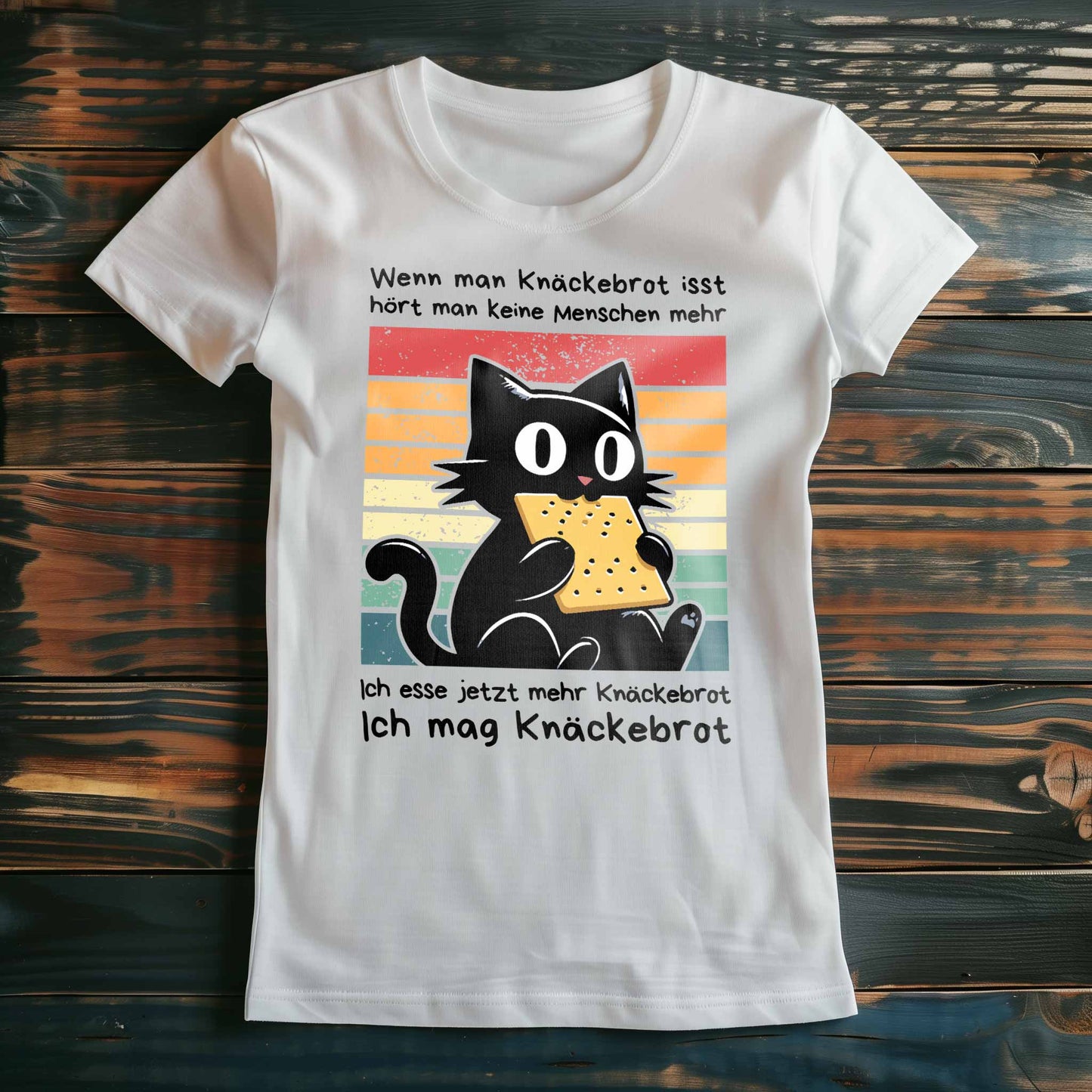 Weißes Damen-Shirt auf Holzboden mit Design einer schwarzen Katze und dem Spruch 'Ich mag Knäckebrot'