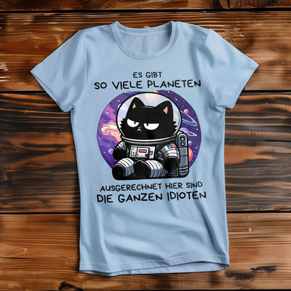 Himmel-Blaues Damen-Shirt auf Holzboden mit Design einer Astronauten-Katze im Weltraum und dem lustigen Spruch 'Es gibt so viele Planeten, ausgerechnet hier sind die ganzen Idioten'