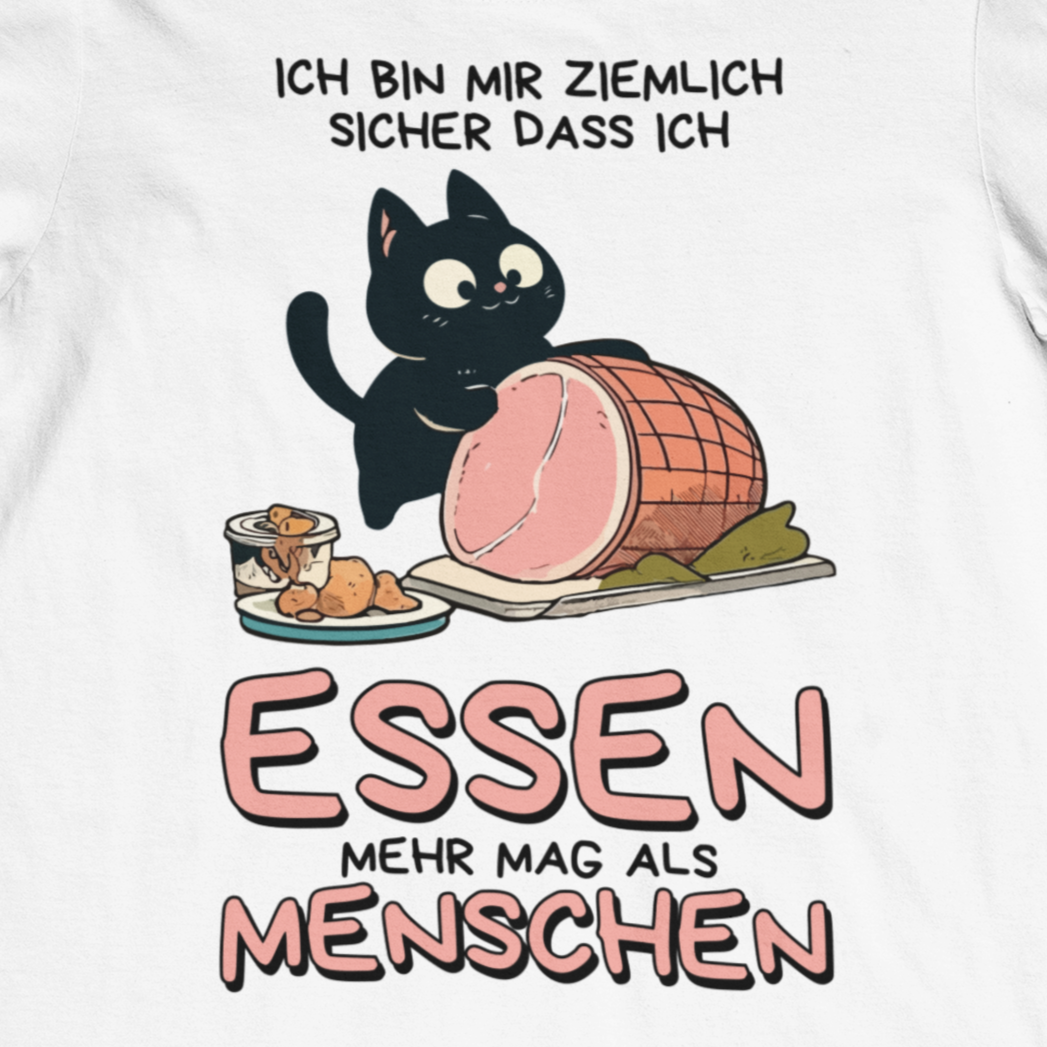 Nahaufnahme eines weißen T-Shirts zeigt ein Design einer schwarzen Katze mit einem Schweinebraten und dem lustigen Spruch: 'Ich bin mir ziemlich sicher, dass ich Essen mehr mag als Menschen'