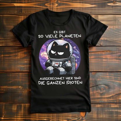 Schwarzes Damen-Shirt auf Holzboden mit Design einer Astronauten-Katze im Weltraum und dem lustigen Spruch 'Es gibt so viele Planeten, ausgerechnet hier sind die ganzen Idioten'