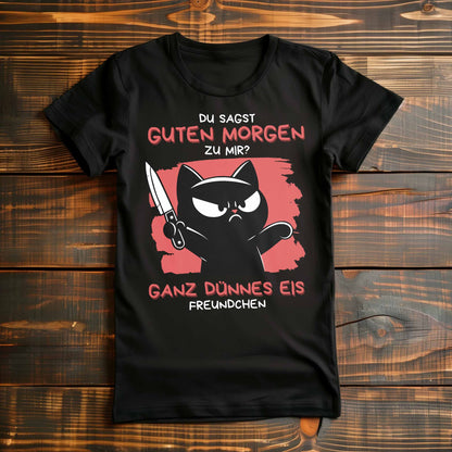 Schwarzes Damen-T-Shirt auf Holzboden mit Design einer schwarzen Katze mit Messer und dem lustigen Spruch 'Guten Morgen? Ganz dünnes Eis'