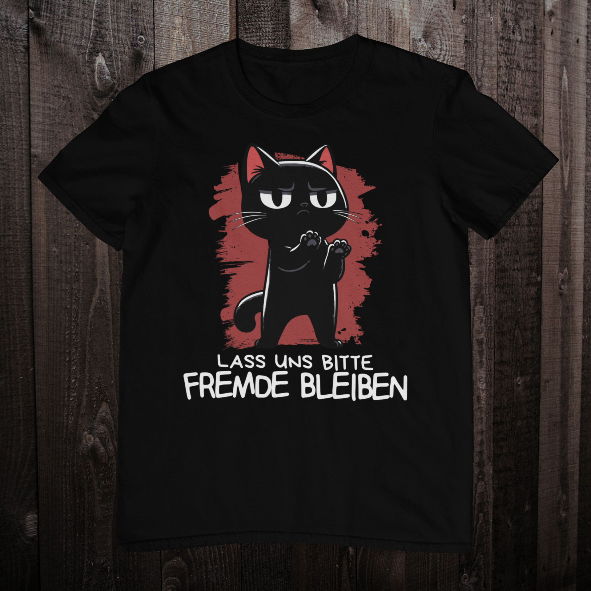 Schwarzes T-Shirt auf einem dunklen Holzboden mit einer schwarzen Katze und dem lustigen Spruch 'Lass uns bitte Freunde bleiben'