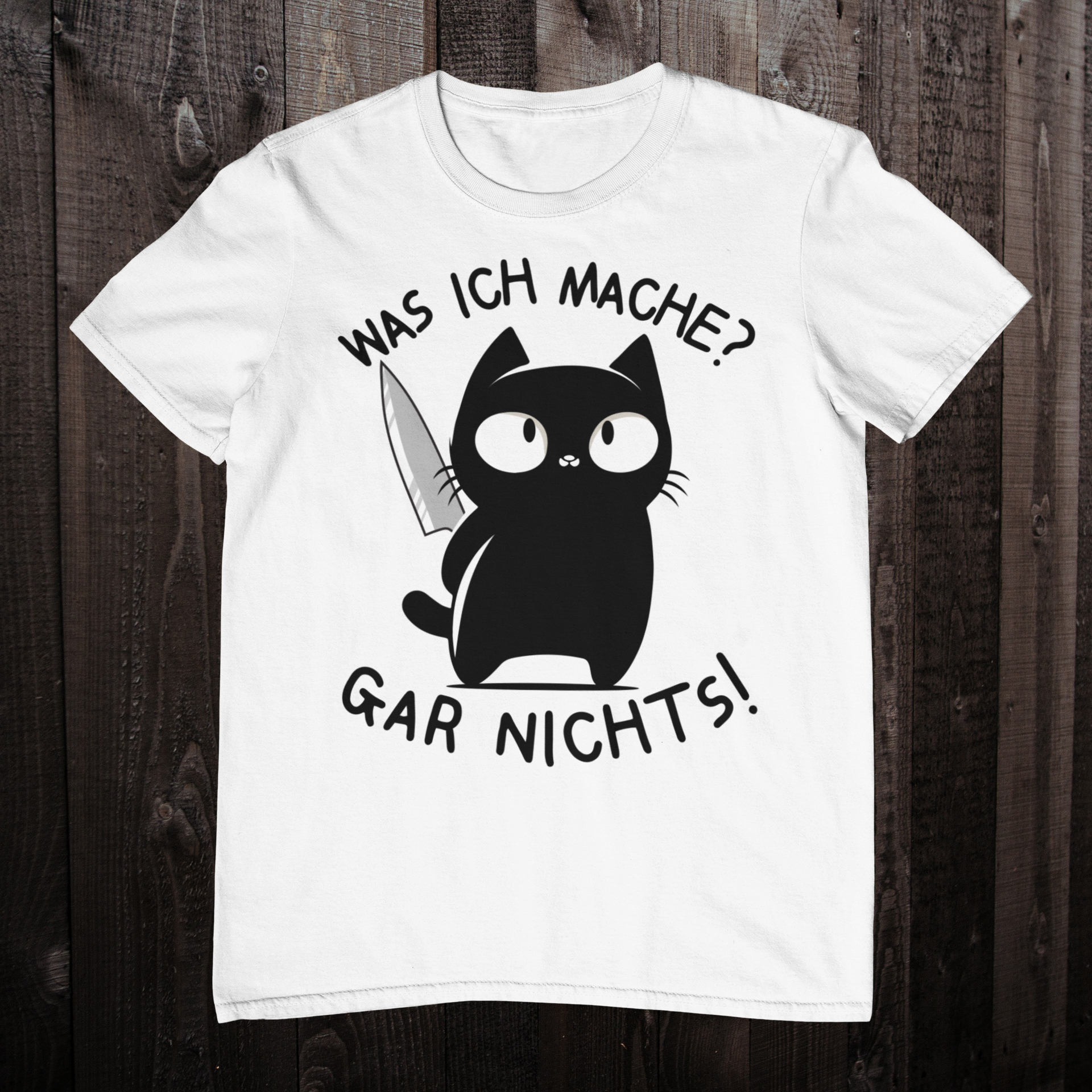 Weißes T-Shirt auf einem dunklen Holzboden mit einer schwarzen Katze, die ein Messer versteckt und dem lustigen Spruch 'Was ich mache? Gar nichts!'